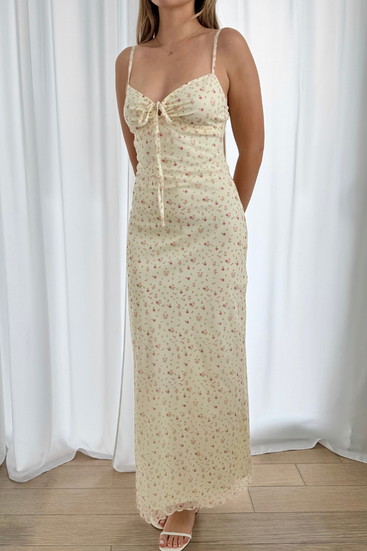 Woman wearing a mesh floral dress against a white curtain background