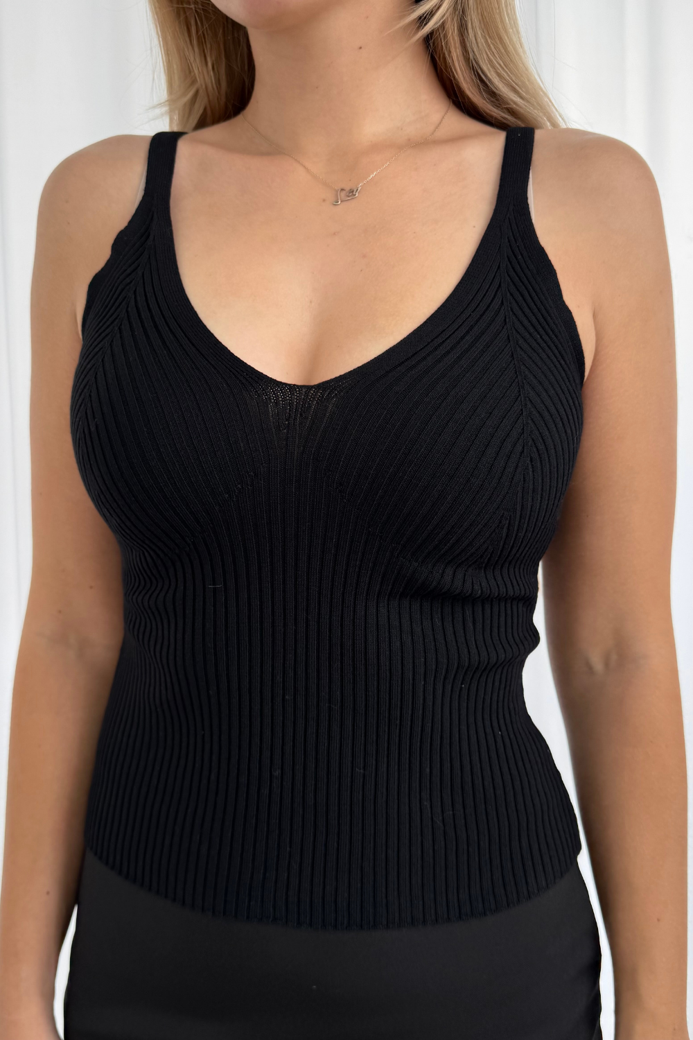 Black ribbed tank top worn by a person against a white background
