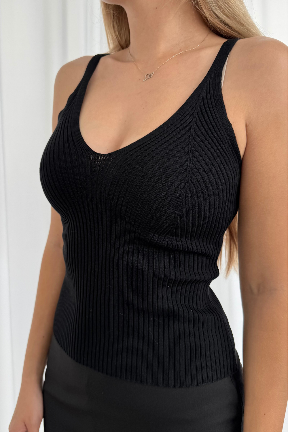 Black ribbed tank top worn by a person against a white background